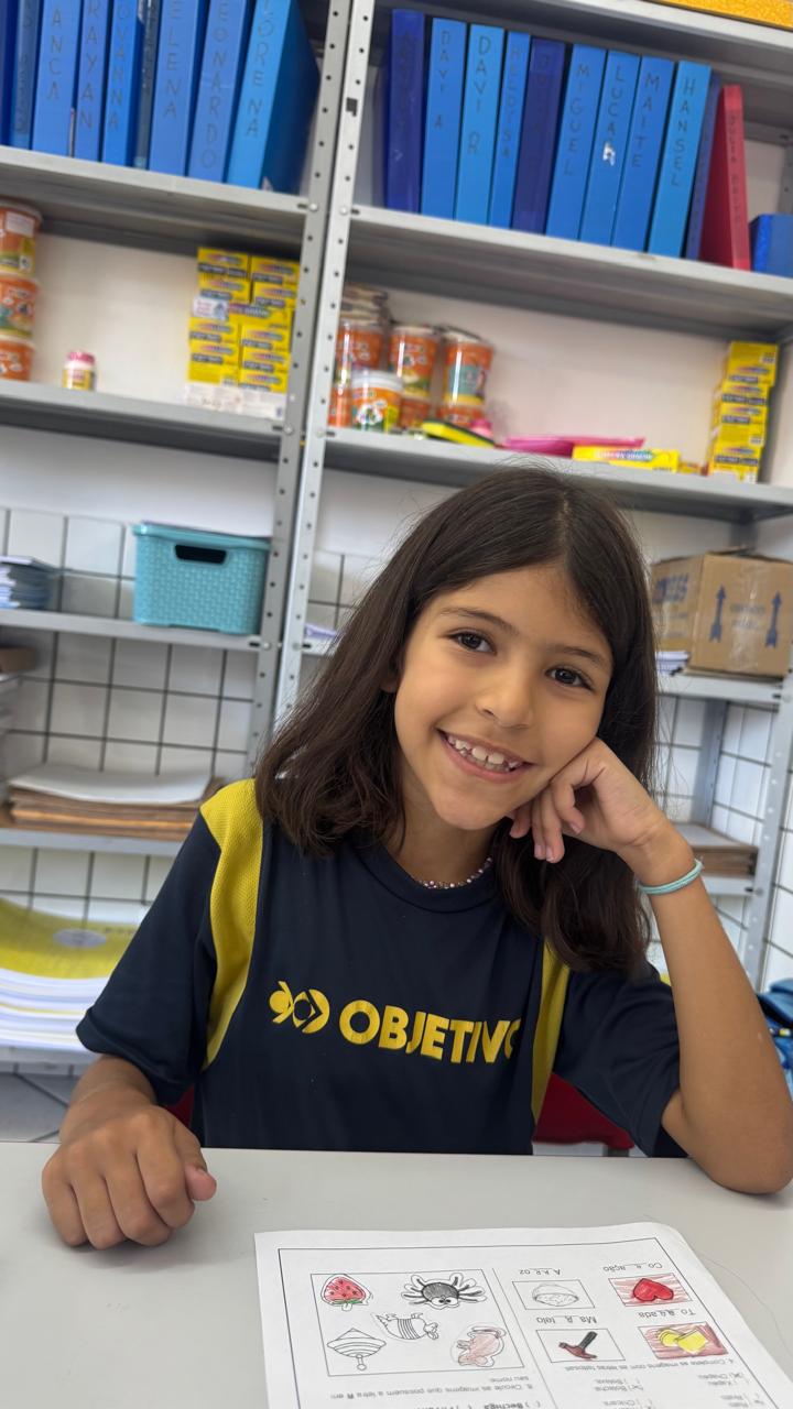 Aluna do Ensino Fundamental sorrindo na carteira durante uma atividade