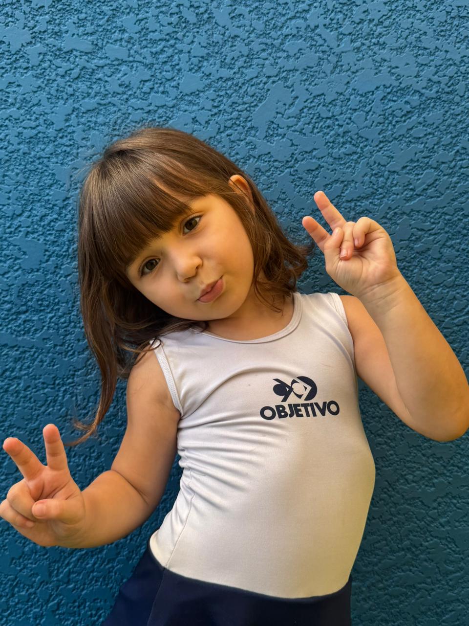 Aluna da Educação Infantil sorrindo com uniforme do Objetivo